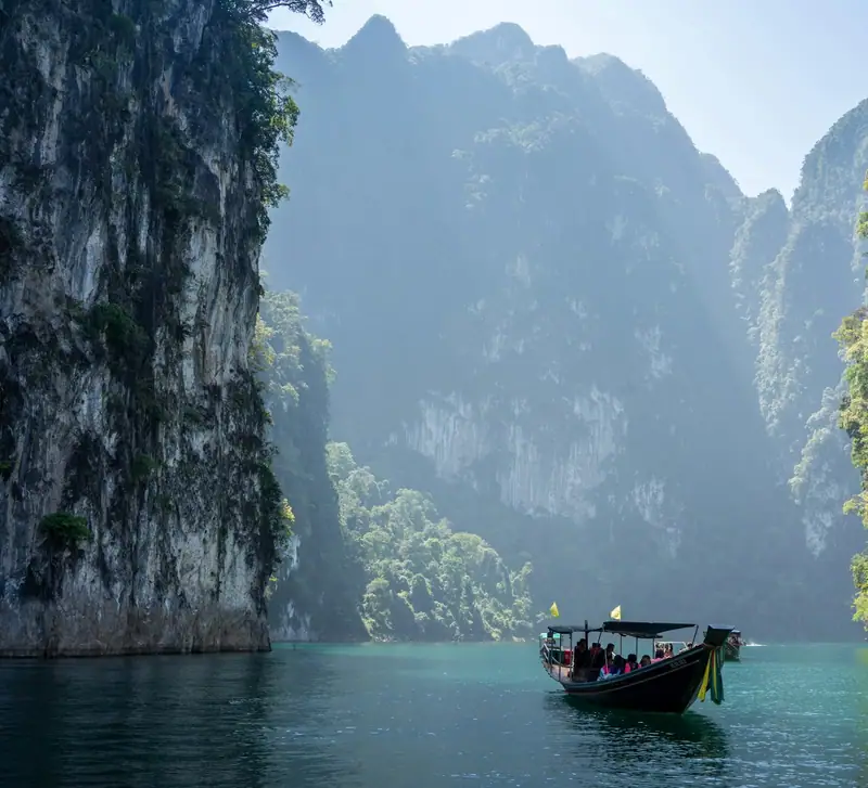 Longtail boat between limestone cliffs