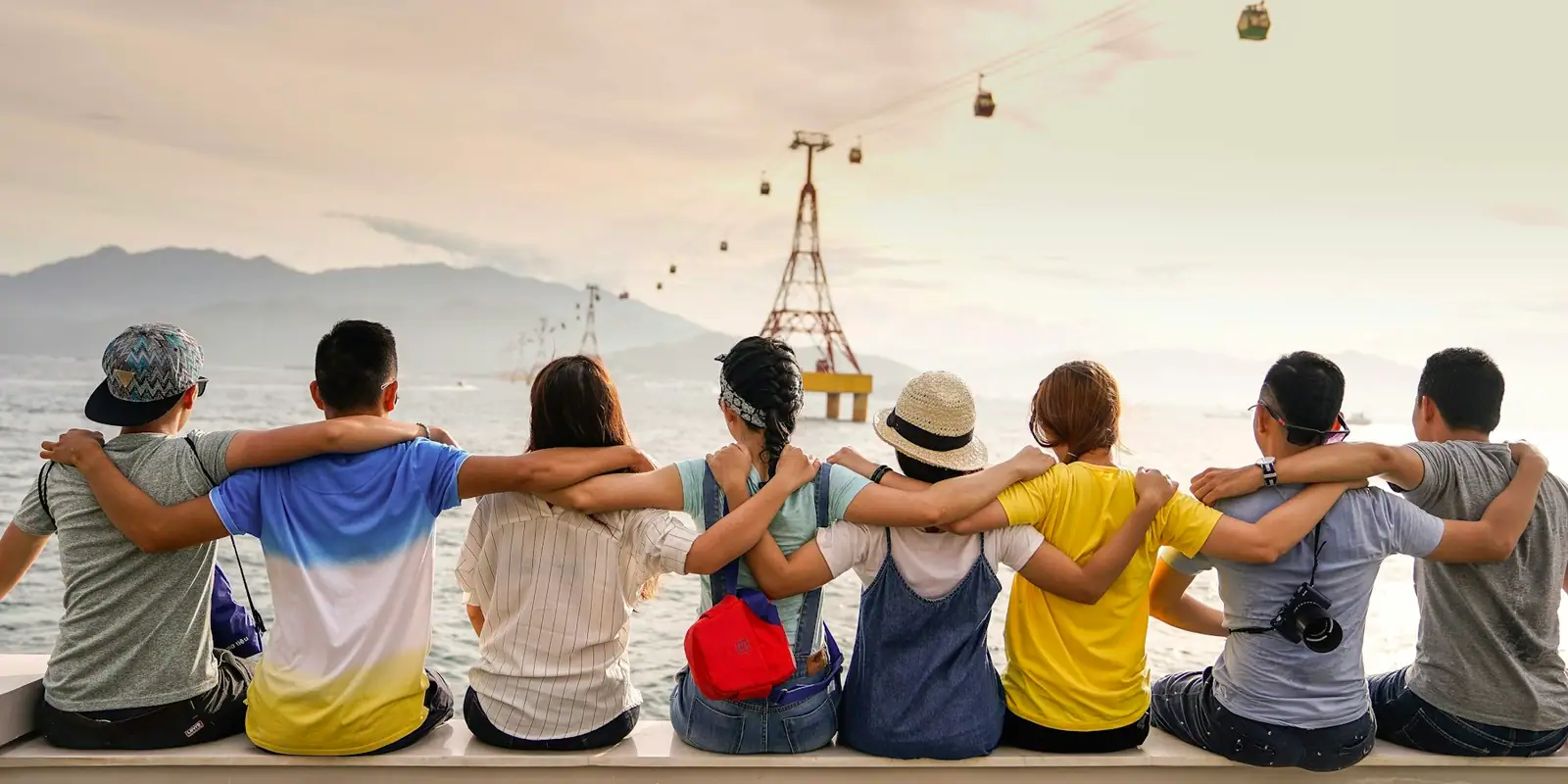 Friends sitting together on a wall at a viewpoint